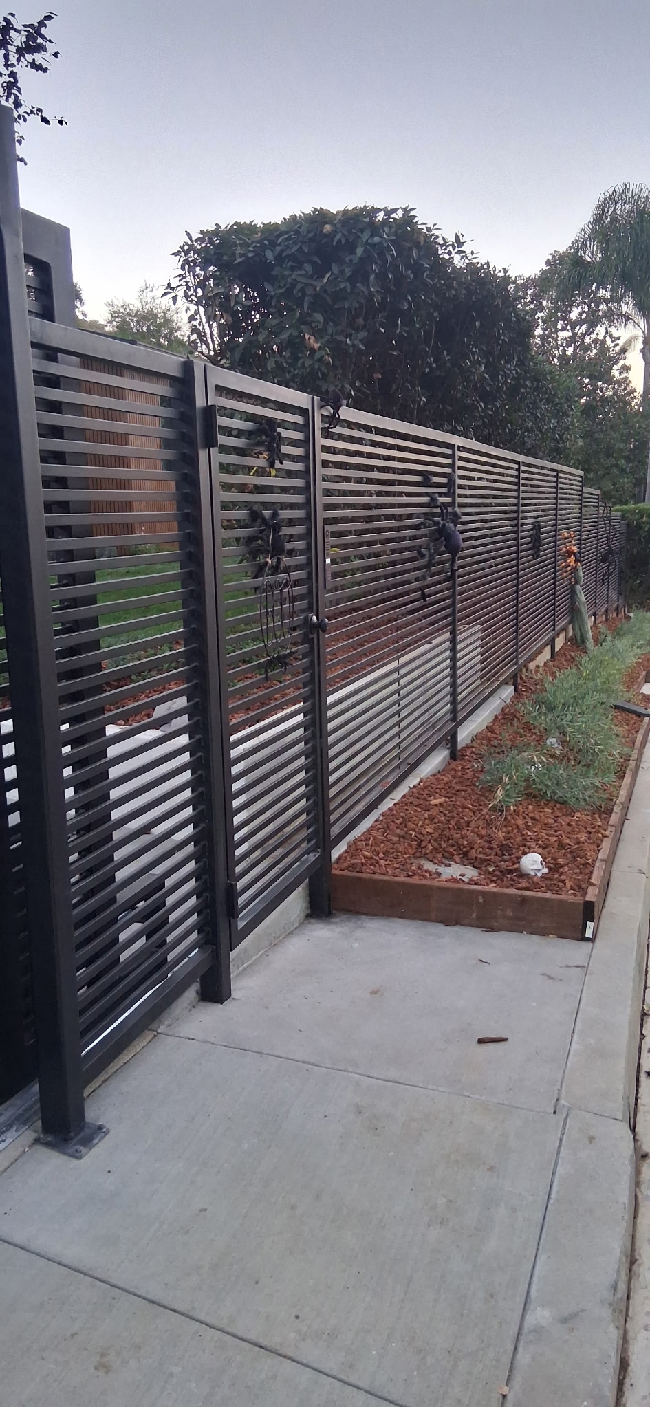 Modern horizontal-slat steel driveway gate and fence